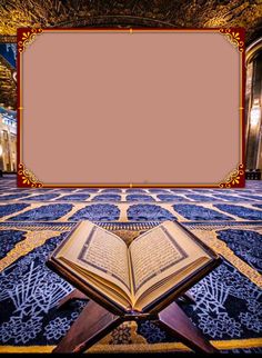 an open book sitting on top of a blue and gold carpet with a red frame