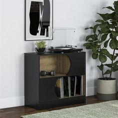 a record player sitting on top of a black cabinet next to a potted plant