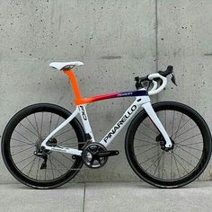 a white and orange bike leaning against a wall