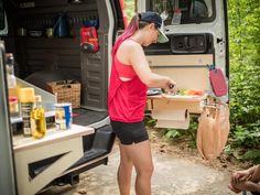 a woman is preparing food in the back of a van