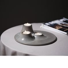 two candles are sitting on top of a round table next to a book and magazine