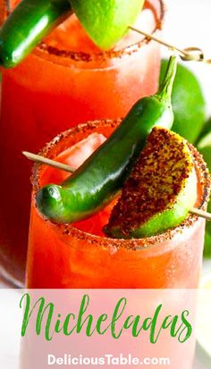 two glasses filled with drinks and garnished with green peppers, limes and chili