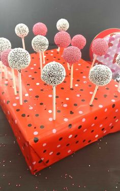 cake pops are sitting on top of an orange gift box with polka dot print paper