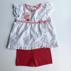 Sweet Outfit for Baby of Eyelet Shirt with Picnic Embroidery and Matching Red Shorts. Eyelet shirt with red and white gingham trim around collar, and below chest with a bow. Picnic embroidered as well as fruit and flowers, gingham print apple. Ruffle cap sleeves and along hem and draping. 1 button closure. Red shorts have elastic waist band. Size: 12 months Brand: Fisher Price Please view my shop! New items added often: https://www.etsy.com/shop/AutumnRoseArtVintage Casual Cotton Gingham Sets, Casual Gingham Cotton Sets, Summer Gingham Short Sleeve Sets, Summer Gingham Sets With Short Sleeves, Summer Embroidered Short Sleeve Sets, Embroidered Short Sleeve Summer Sets, Gingham Cotton Short Sleeve Set, Gingham Cotton Set With Short Sleeve, Embroidered Cotton Short Sleeve Sets