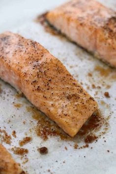 two cooked salmon fillets sitting on top of a white plate covered in seasoning