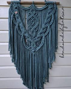 a blue wall hanging on the side of a building with fringes and beads attached to it