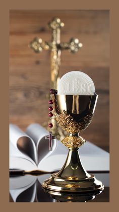 a gold chalice with beads and a rosary on it next to an open book