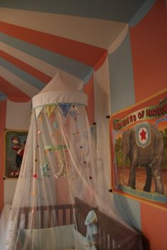 a baby's room decorated in pink, blue and white with an elephant bed canopy