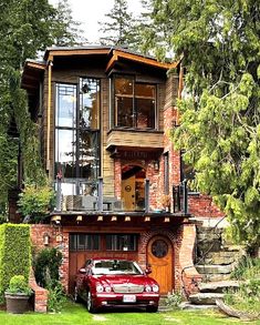 a red car is parked in front of a large house with stairs leading up to the second story