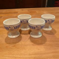 four blue and white bowls sitting on top of a wooden table