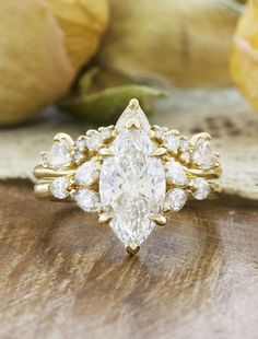 a close up of a diamond ring on a wooden surface with pears in the background