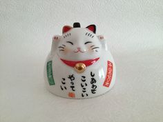 a small white cat figurine with chinese writing on it's face and eyes