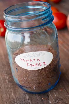 a glass jar filled with food sitting on top of a wooden table next to tomatoes