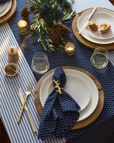 the table is set with blue and white plates, silverware, pineapples, and candles