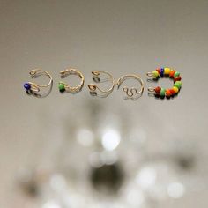 three pairs of earrings sitting on top of a table next to a wine glass filled with liquid