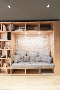 a couch sitting in front of a wooden book shelf filled with books and other items