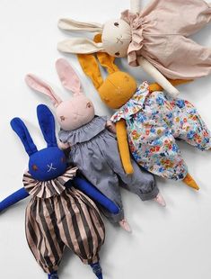 four stuffed animals laying next to each other on top of a white surface with different patterns and colors