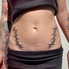 a woman's stomach with tattoos on it and the bottom part of her belly