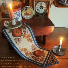 a table topped with a candle next to a clock and other items on top of a wooden table