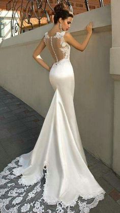 a woman in a white wedding dress is standing on a balcony with her back to the camera