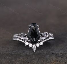 a black and white diamond engagement ring on top of a stone surface with diamonds around it