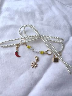 a white beaded necklace with charms attached to it on top of a white sheet