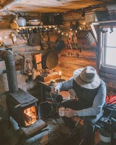 a man sitting in front of an open fire place next to a wood burning stove