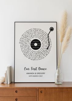 a poster with the words our first dance on it next to some books and a vase