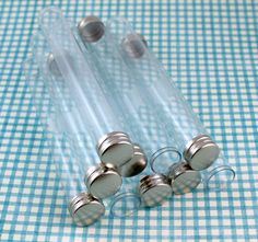 four glass jars with silver lids on a blue and white checkered tablecloth