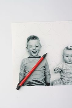 a pencil is laying on top of a photo with a baby and heart shapes in the background