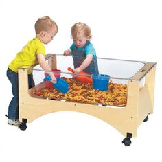 two young children playing with toys in a play table