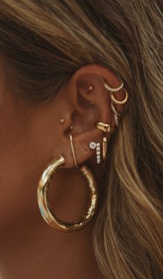 a woman wearing ear piercings and gold rings