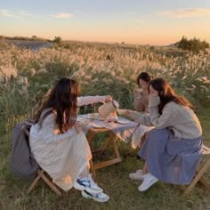 two women sitting at a table in the middle of a field