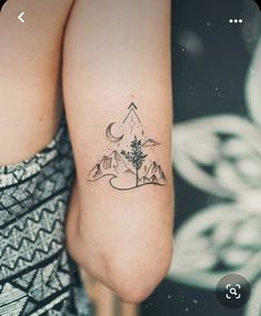 a woman's arm with a tattoo on it that has mountains and a tree