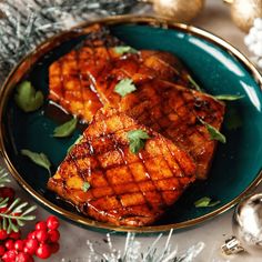 two pieces of grilled meat on a blue plate next to silver and red ornaments