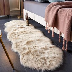 a white sheepskin rug on the floor next to a bed