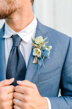 a man wearing a blue suit with a boutonniere on his lapel