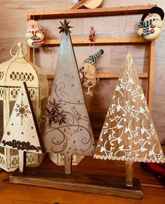 three wooden christmas trees sitting on top of a wooden shelf next to other ornaments and decorations