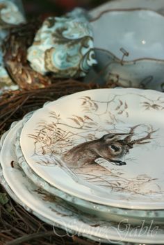 a stack of plates sitting on top of a wicker basket filled with leaves and twigs