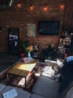 a living room filled with furniture and a flat screen tv mounted to the side of a brick wall