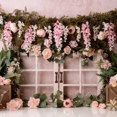 pink flowers and greenery are arranged on the wall in front of an old window