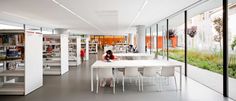 a woman is sitting at a table in the middle of a room filled with books