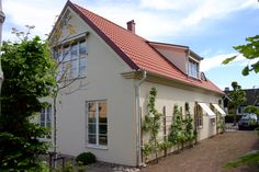 a white house with a red roof and ivy growing on it's side wall