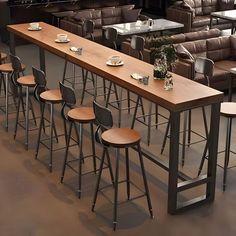 a long table with stools and plates on it in a room full of couches