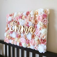 the name emo spelled in gold letters surrounded by pink and white flowers on a black crib