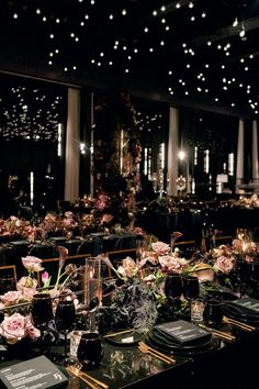 the tables are set up with black linens and flowers in vases on them