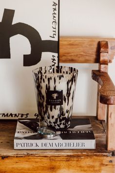 a stack of books sitting on top of a wooden table next to a glass vase