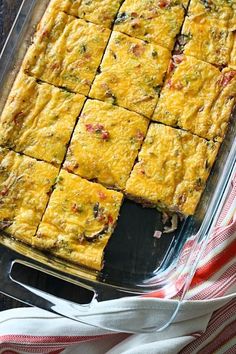 a casserole dish filled with lots of cheese and toppings, on top of a red and white striped cloth