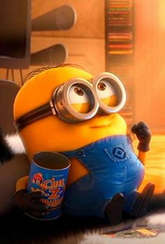 a yellow and black minion sitting on top of a bed next to a cup