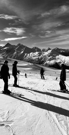 several skiers are standing in the snow with mountains in the background